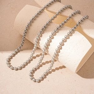 Detailed view of long grey pearl necklace draped on elegant beige geometric props