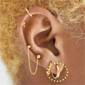 Macro shot of minimalist gold S925 silver wave hoop earrings on ear with fine chain details