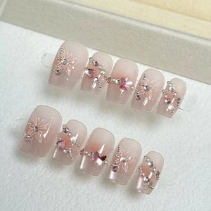 Handmade pink gradient press-on nails with butterfly charms and pearl rhinestone details