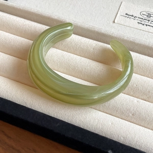 Detail of light green translucent resin cuff bracelet with jade texture in display box