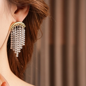 Close-up of golden moon fringe earring with sparkling crystals on model's ear