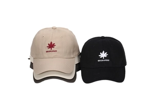 Close-up of maple leaf and GOLDPARKO embroidery on beige and black baseball caps