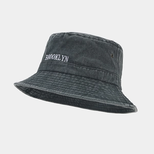 Détail de la broderie Brooklyn et des œillets sur le bob en coton gris délavé