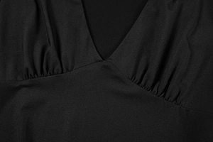 Detail of elegant black dress showing deep V-neckline and intricate gathered pleated waist