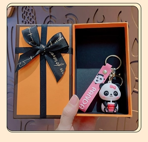 Cartoon panda keychain with pink strap in an orange gift box for accessory detail