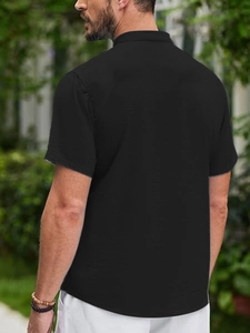 Detailed back view of a black men's polo shirt featuring textured waffle fabric weave