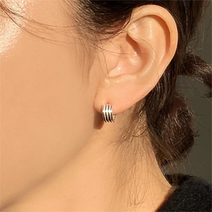 Close-up of minimalist layered silver hoop earrings worn on a model in natural light