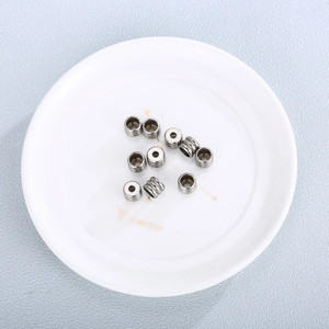 Ten pieces of silver stainless steel spring coil beads for DIY jewelry making on a white plate