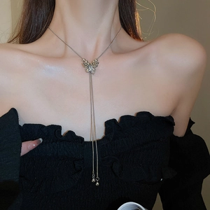 Detail of silver butterfly pendant necklace with long tassel chain on a model neck