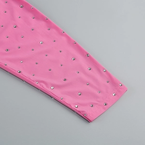 Detail shot of sparkling rhinestones and ruched texture on a pink high-neck party dress