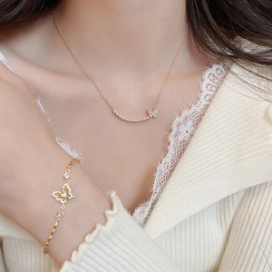 Close-up of 18k gold butterfly necklace and pearl bracelet set on a model