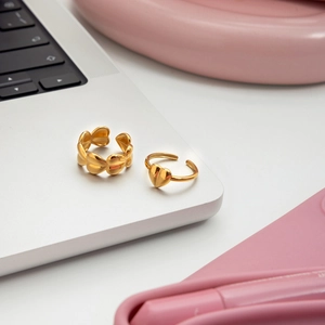 Macro detail of adjustable gold-plated heart-shaped rings on a laptop surface