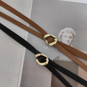 Detail of minimalist black and brown leather belts with irregular gold metal rings