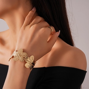 Detailed close-up of golden floral textured bangle and ring set worn by a model