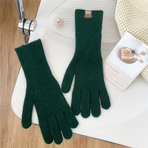 Close-up of dark green knitted wool gloves with rib texture and brown leather label