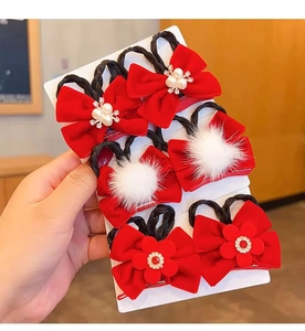 Detail of red bow hair clips with pearls, pom-poms, and floral decor for girls