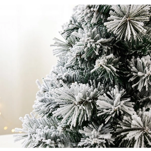 Close-up of thick white flocking on green needles of a tabletop cedar Christmas tree