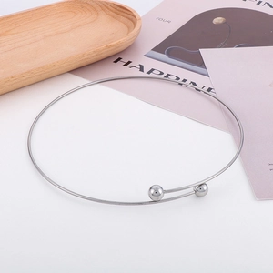 Close-up of a silver minimalist open choker featuring spherical ends on a wooden tray