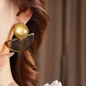 Close-up of bohemian fan-shaped resin drop earrings worn by a model in soft lighting