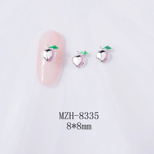 Macro detail of silver peach nail charm with green leaf and purple gradient finish