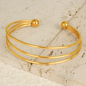 Macro shot of 18K gold plated stainless steel triple layered open cuff on stone background