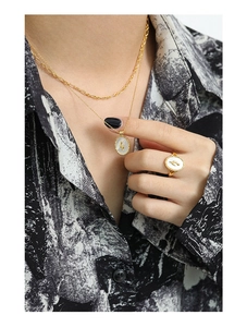 Detail of gold tulip shell pendant necklace and matching ring on model's outfit