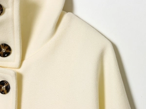 Detailed close-up of cream wool blend coat with elegant dark marble buttons