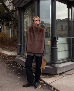 Gilet en fausse fourrure marron à col montant porté sur un blazer gris en décor urbain