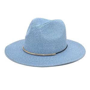 Detail of blue fedora straw hat featuring a black decorative band and gold metal bar