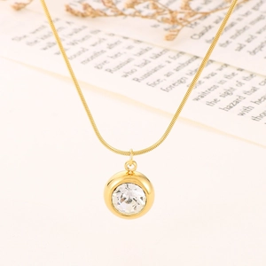 Elegant gold snake chain necklace featuring a round crystal pendant on a beige surface