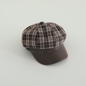 Close-up of retro plaid baker boy hat with brown leather brim and wool tweed texture