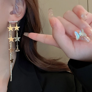 Gros plan de boucles d'oreilles étoiles dorées à franges portées par un mannequin