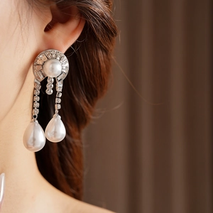 Macro shot of silver drop earrings with elegant pearls and sparkling crystals on model