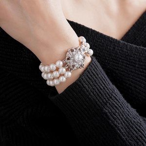 Detail of three-row pearl bracelet with ornate silver floral clasp on model wrist