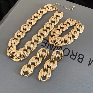 Detailed set of gold chain necklace, bracelet and earrings on a gray jewelry gift box