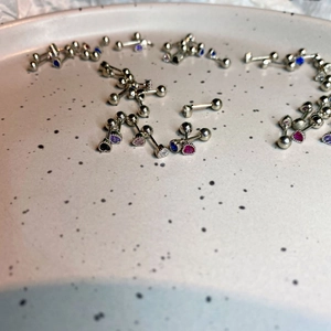 Macro view of colorful heart zircon stud earrings with screw ball backs on a ceramic tray