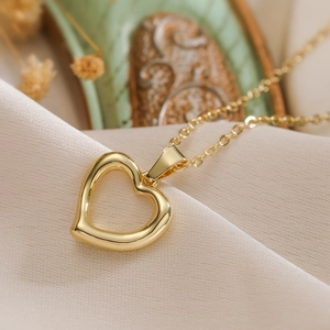 Minimalist gold hollow heart pendant necklace with elegant chain on a soft fabric backdrop