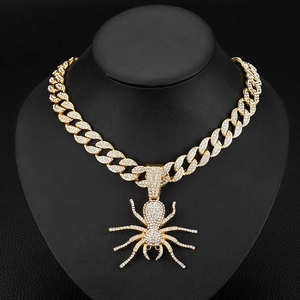 Close-up of gold hip hop Cuban chain featuring a large iced-out spider pendant with crystals