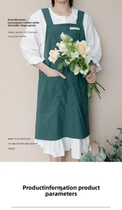 Detail of dark green cotton apron featuring wide shoulder straps and a large utility pocket