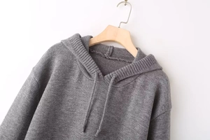 Detail of dark grey knit texture on loose long-sleeved hooded sweater with drawstring