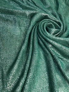 Macro detail of the sparkling green metallic fabric with elegant draped texture for shawls