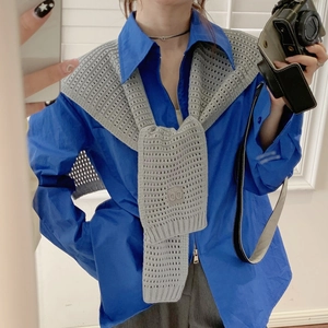 Detail showing a grey knitted shawl tied over a blue casual shirt on a female model