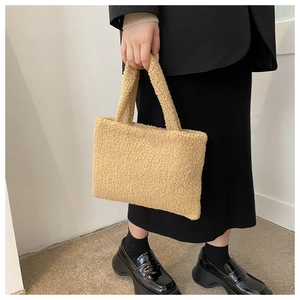 Detail of khaki plush tote bag held by model, showcasing fuzzy texture and warm winter style