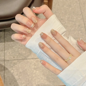 Hand-painted press-on nails with nude gradient, gold glitter, and pearl bow accents