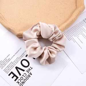 Detail of elegant champagne satin silk scrunchie on a vintage paper and wood tray