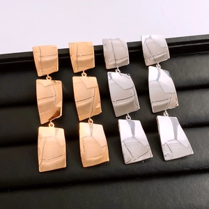 Detailed macro view of long tassel square earrings in gold and silver finish options