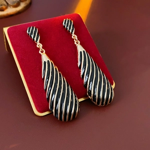 Vue macro de boucles d'oreilles rayées noir et or sur support en velours rouge