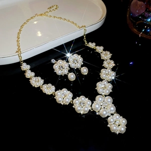 Detail of floral pearl necklace and earrings set with gold finish on black background