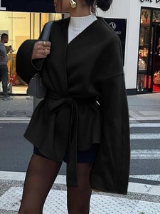 Détail d'un blazer noir noué pour femme avec col en V et ceinture élégante assortie