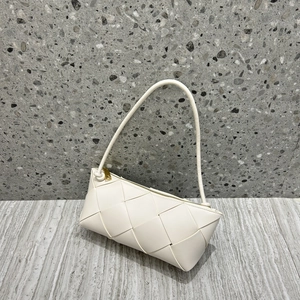 Detail of white woven leather handbag with gold triangle zipper on terrazzo background
